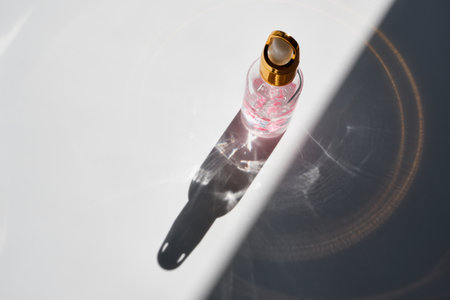 Cosmetic product bottles with rose petals and hard shadow. Skincare beauty product conceptの写真素材