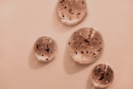 Serum drops with gold particles close-up in mocha mousse color