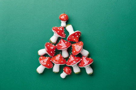 Ceramic Amanita muscaria inspired ornaments arranged in a christmas tree shape on green backgroundの写真素材