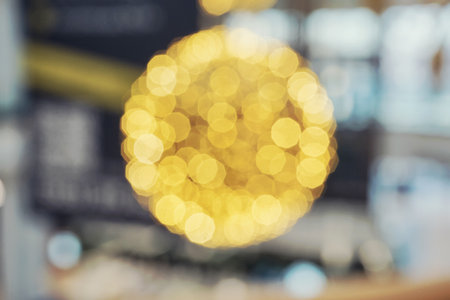 Golden bokeh lights forming sphere against blurred urban backgroundの写真素材