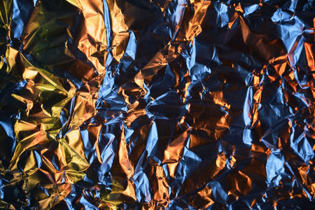 Crumpled metallic foil texture creating an abstract background with vibrant light reflections