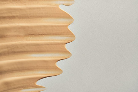 Beige liquid foundation creating textured smeared swatch on light background