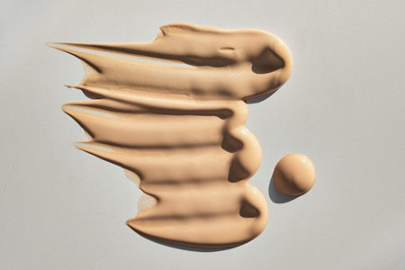 Liquid foundation cosmetic product showing textured smears and drop