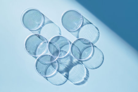 Several petri dishes casting long shadows on light blue background