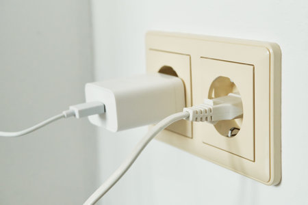 White charger and cable connected to double power outlet on white wall
