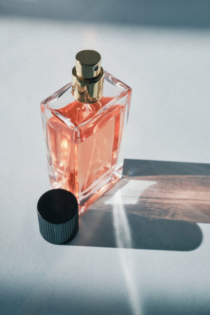 Elegant glass perfume bottle reflecting light on white background