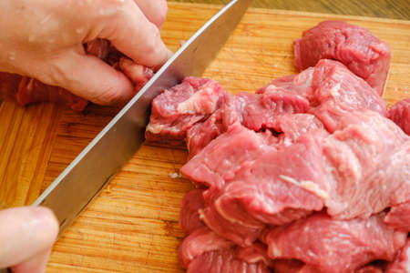 Butcher cutting pork meat on kitchenの写真素材