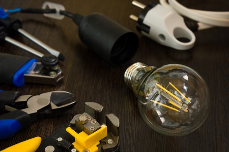 burning light bulb and socket and other electrician tools are on the tableの写真素材