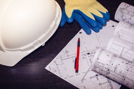 white helmet, gloves, and drawings are on the tableの写真素材