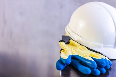 white helmet, gloves, and drawings are on the table