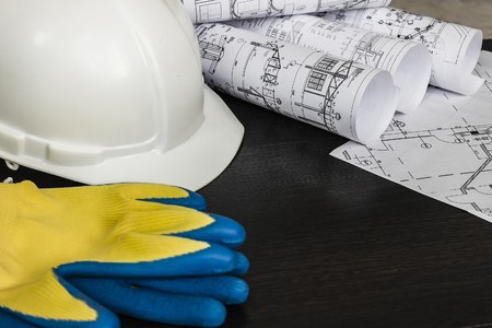 white helmet, gloves, and drawings are on the tableの写真素材