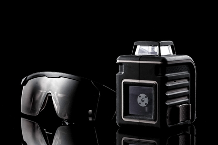 Modern laser level and special glasses are on the table on a black background. Can be used as a...