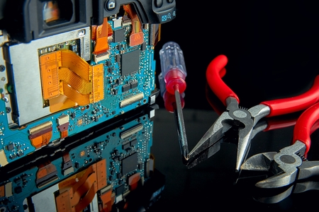 Concept disassembly and repair of digital SLR camera close-up on black glass with tools.の写真素材