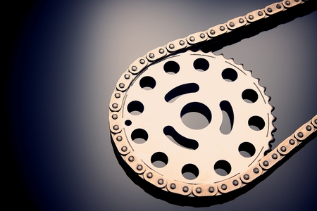 Roller chain with sprocket on dark background. It is used on cars, motorcycles, bicycles and in mechanical engineering. Can be used as a backgroundの写真素材