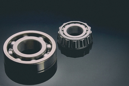 Close-up of a set of ball and roller bearings for repair lying on the desktop in the dark. Can be used as a backgroundの写真素材