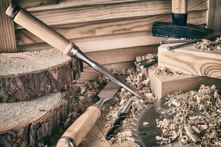 A set of chisels, drills on wood and boards lies on a dark background.