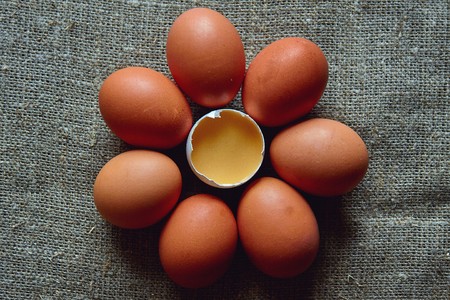 Fresh village chicken eggs lie on the surface of the table with a wooden spoon, one broke.の写真素材