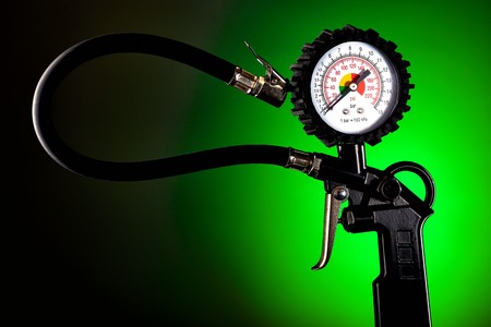 the pressure gauge of the compressor to control the pressure in the tires on a dark background closeupの写真素材