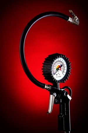 the pressure gauge of the compressor to control the pressure in the tires on a dark background closeupの写真素材