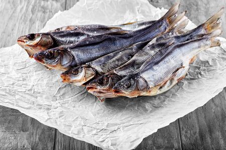 Fresh hot and cold smoked fish lies on a paper napkin on a wooden tableの写真素材