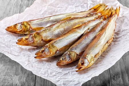 Fresh hot and cold smoked fish lies on a paper napkin on a wooden tableの写真素材