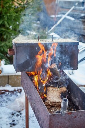 A hand-made smokehouse for hot Smoking stands on a fire for cooking meat and fishの写真素材