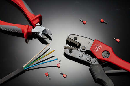 Crimping tool for an electrician on a dark background. Press the pliers or pliers for the bushing...