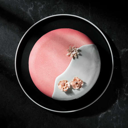 Delicate natural mousse cake with berries and nuts, covered with colored glaze on a dark background. A real festive decorationの写真素材
