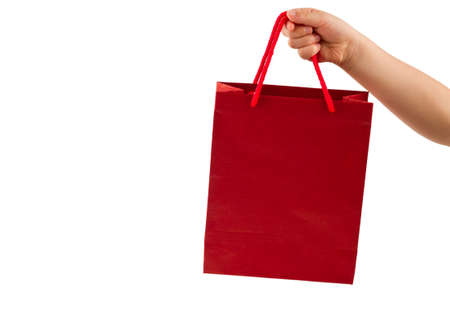 Red shopping bag in child hand isolated on white backgroundの写真素材