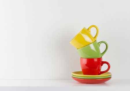 Colorful cups on white wooden shelfの写真素材