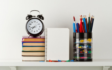 School supplies and alarm clock on white shelfの写真素材