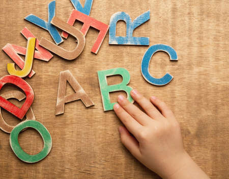 Colorful wooden letters with child handの写真素材
