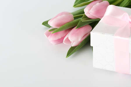 Pink fresh tulips and gift box on white backgroundの写真素材
