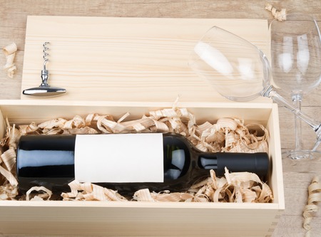 Bottle of red wine in wooden box and empty wine glassesの写真素材