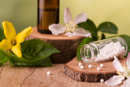 Bottle of homeopathic globules,homeopathic remedies and flowersの写真素材