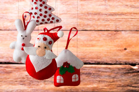 Christmas decoration, holidays, new year and decor card. New Year's fir tree toys on a wooden background. Santa Claus, bunny, house, spruce, decorations and toys.の写真素材