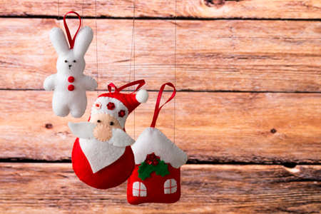 Christmas decoration, holidays, new year and decor card. New Year's fir tree toys on a wooden background. Santa Claus, bunny, house, spruce, decorations and toys.の写真素材