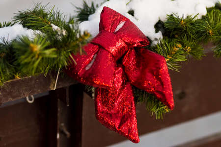 Red bow and fir branches.. Christmas decoration on the street. Wooden backgroundの写真素材