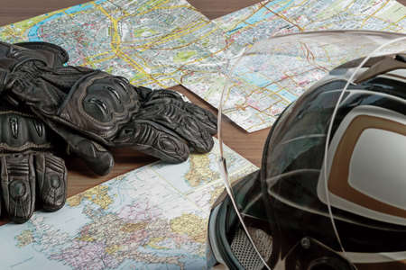 Motorcycle helmet, gloves, and road maps on a wooden table. Journey Dream. Travel route.の写真素材