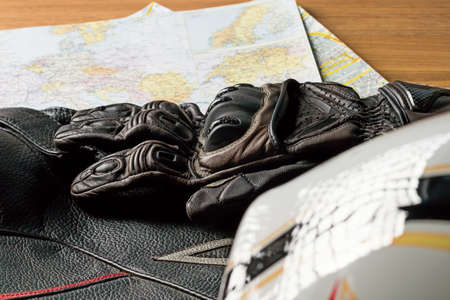 Motorcycle helmet, gloves, and road maps on a wooden table. Journey Dream. Travel route.の写真素材