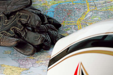 Motorcycle helmet, gloves, and road maps on a wooden table. Journey Dream. Travel route.