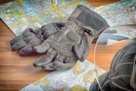 Motorcycle helmet, gloves, and road maps on a wooden table. Journey Dream. Travel route.の写真素材