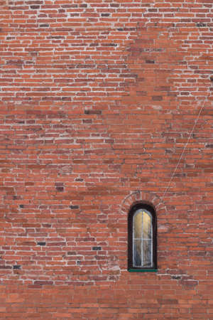 Texture of old brick wall with a small window. Red brick wall background with small window.の写真素材