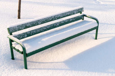 Green bench in a park covered with snow. Winter in Russia.の写真素材
