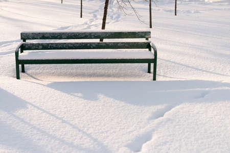 Green bench in a park covered with snow. Winter in Russia.の写真素材