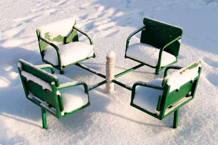 Children carousel with snow. Bright green carousel at the playground under snowの写真素材
