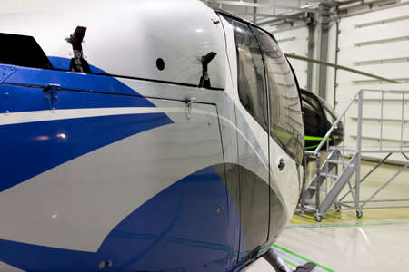 Small private helicopter. Helicopter parked in the hangar. Detail of the cab. Parking of helicopters at the airport.の写真素材