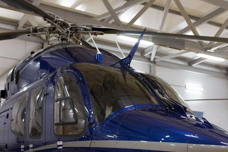 Small private helicopter. Helicopter parked in the hangar. Detail of the cab. Parking of helicopters at the airport.の写真素材