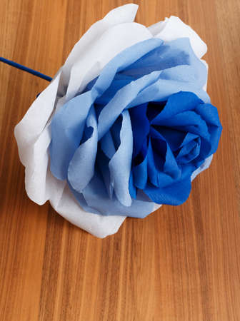 Picturesque paper rose. Origami. Giant multicolored handmade paper flower on a wooden background.の写真素材