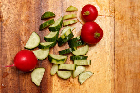 Sliced cucumber and radish on a wooden board. Fresh radishes and cucumber on a wooden boardの写真素材